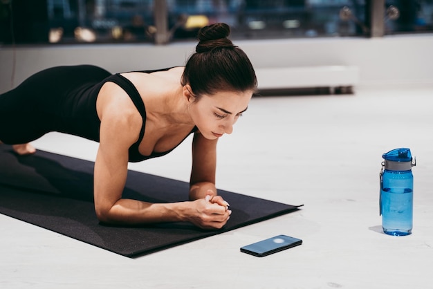 Photo vue latérale d'une femme faisant du planking au gymnase