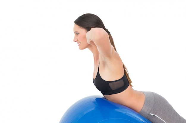 Vue latérale d&#39;une femme en forme qui s&#39;étend sur ballon de fitness