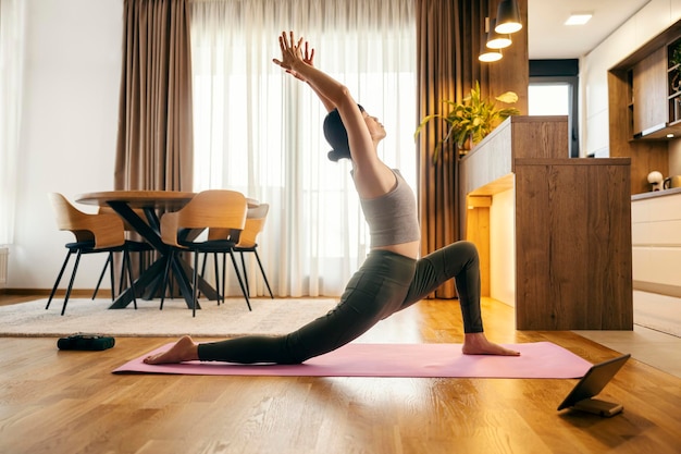 Vue latérale d'une femme japonaise pratiquant le yoga en pose de croissant à la maison