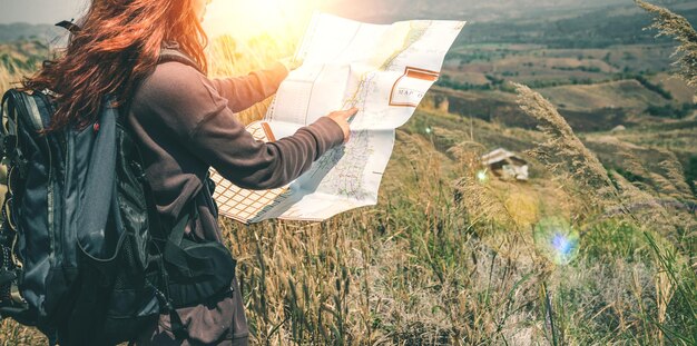 Photo vue latérale d'une femme lisant une carte debout sur une montagne