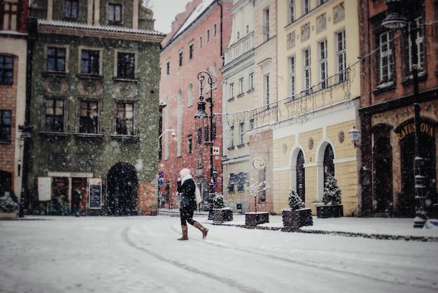 Photo vue latérale d'une femme marchant dans une rue de la ville pendant une chute de neige