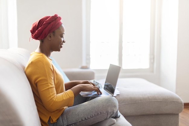 Vue latérale d'une femme noire à l'aide d'un ordinateur portable avec écran vide