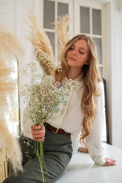 Photo vue latérale femme posant avec des fleurs séchées