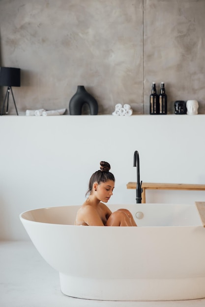 Vue latérale d'une femme prenant un bain moussant à la maison