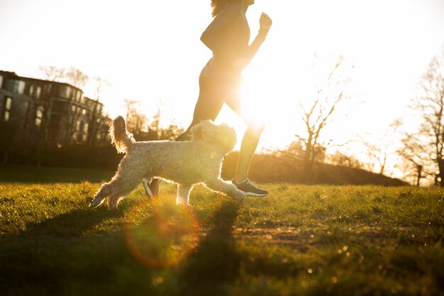 Photo vue latérale femme qui court avec un chien à l'extérieur