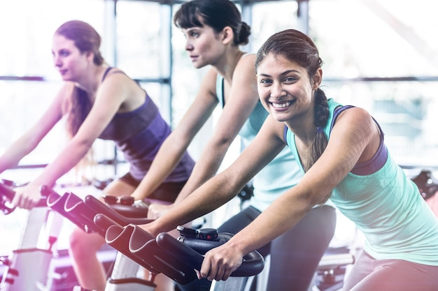 Vue latérale d'une femme qui s'entraîne au cours de spinning dans une salle de sport