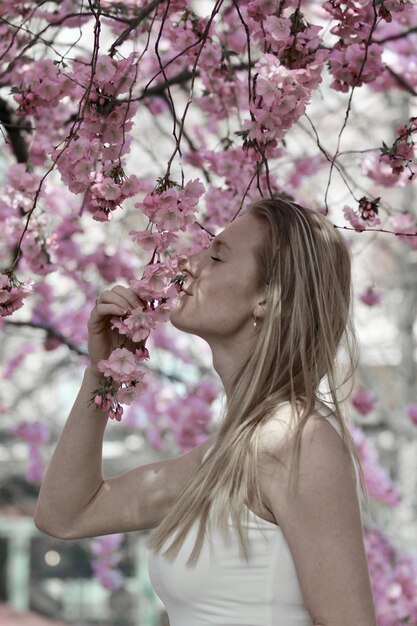 Photo vue latérale d'une femme qui sent les fleurs sur un arbre