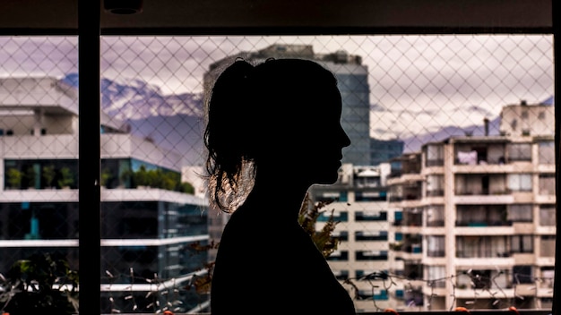 Photo vue latérale d'une femme en silhouette debout près d'une clôture en chaîne