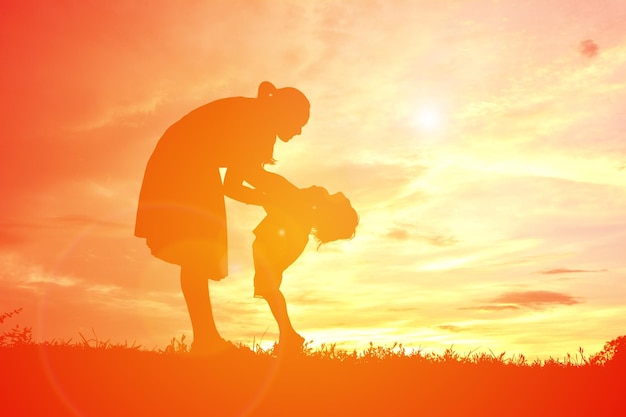 Photo vue latérale d'une femme en silhouette jouant avec un enfant sur le terrain contre le ciel au coucher du soleil