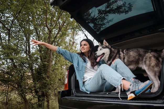 Photo vue latérale d'une femme avec son mignon husky voyageant en voiture