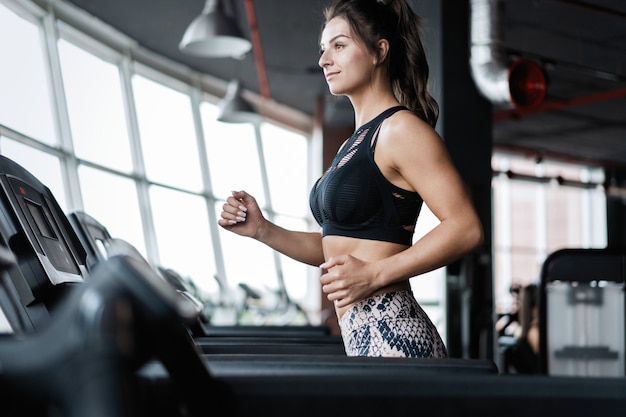 Vue latérale d'une femme sportive attrayante sur une piste de course