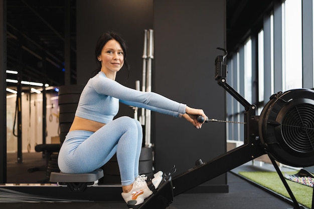 Vue latérale d'une femme sportive faisant de l'exercice sur un rameur