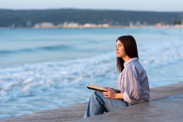 Vue latérale femme tenant un livre avec espace copie