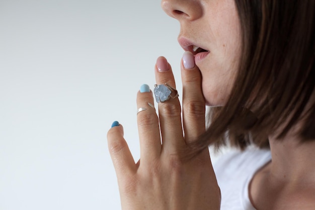 Vue latérale d'une femme touchant ses lèvres avec ses doigts avec deux bagues