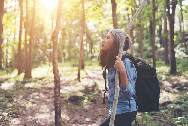 Vue latérale d'une femme touriste réfléchie debout dans la forêt