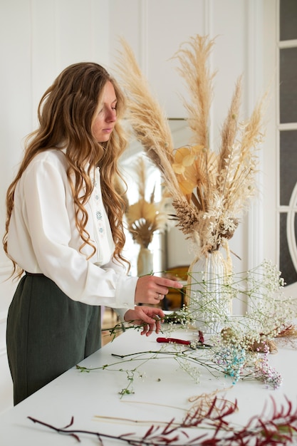 Photo vue latérale femme travaillant avec des fleurs