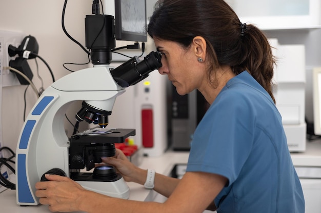 Vue latérale d'une femme vétérinaire regardant à travers le microscope du microscope