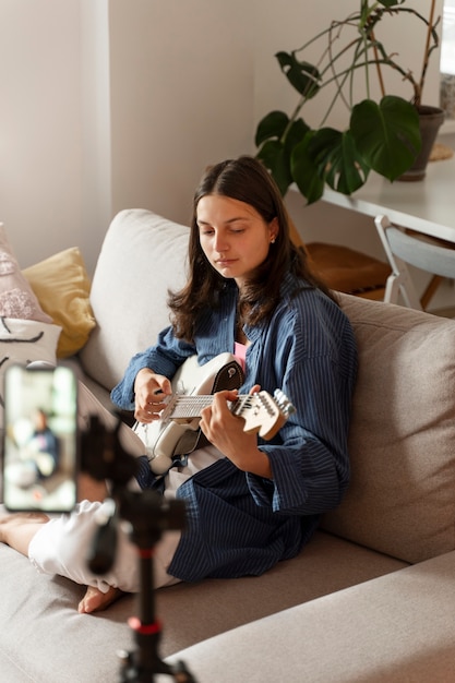 Photo vue latérale fille jouant de la guitare à l'intérieur