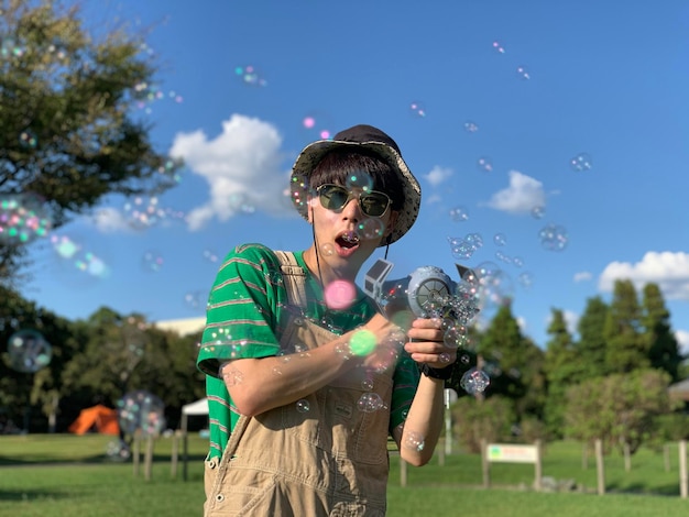 Photo vue latérale d'une fille soufflant des bulles dans le parc