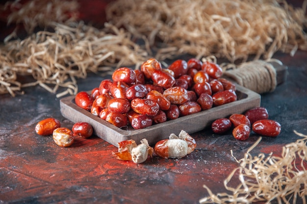 Vue latérale des fruits crus frais à l'intérieur et à l'extérieur d'un plateau en bois sur fond de couleurs mélangées