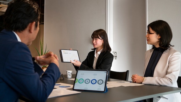 Photo vue latérale des gens d'affaires travaillant avec ipad