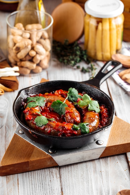 Vue latérale sur une grande saucisse cuite à la sauce tomate dans une casserole castiron