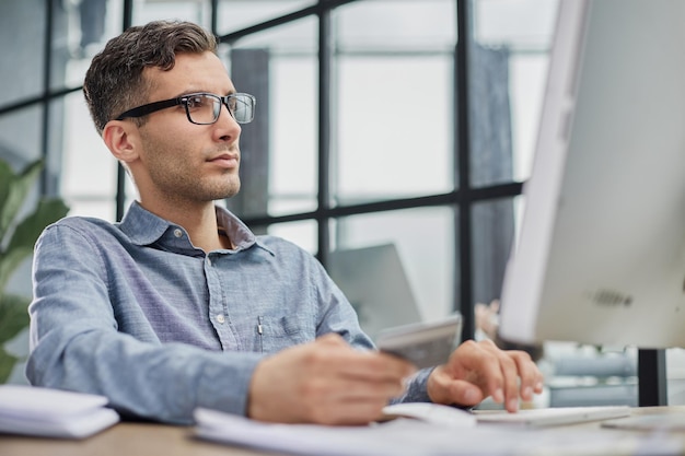 Vue latérale, homme d'affaires PDG utilisant la saisie sur un ordinateur portable travaillant dans un bureau contemporain