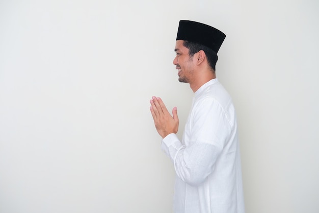 Vue latérale d'un homme asiatique musulman souriant tout en saluant quelqu'un pendant la célébration du Ramadan