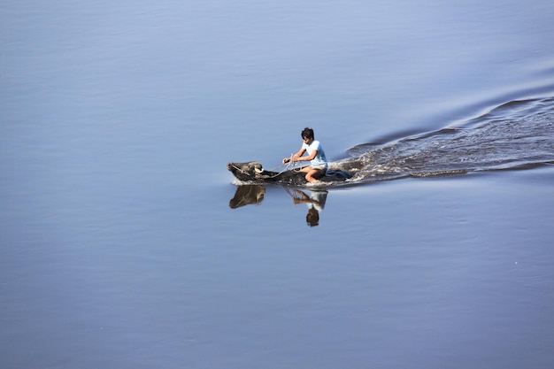 Vue latérale d'un homme assis sur un buffle dans l'eau