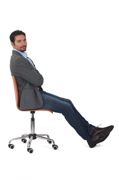 Vue latérale d'un homme assis sur une chaise, regardant la caméra sur fond blanc