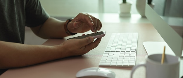 Photo vue latérale de l'homme employé de bureau à l'aide de smartphone sur le bureau