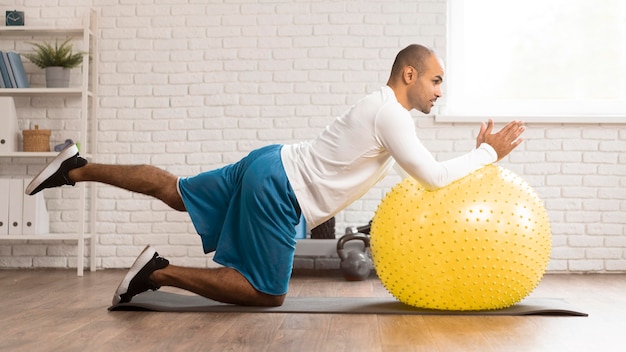 Photo vue latérale de l'homme faisant de la physiothérapie sur ballon