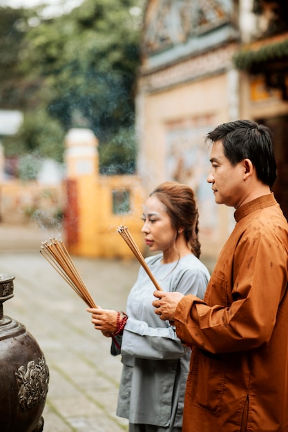 Photo vue latérale de l'homme et de la femme avec de l'encens au temple