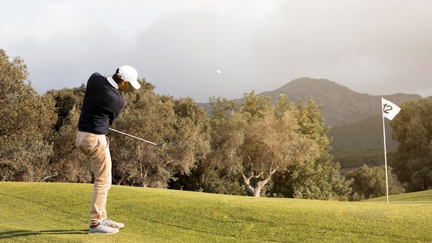 Photo vue latérale de l'homme frappant la balle de golf sur le terrain