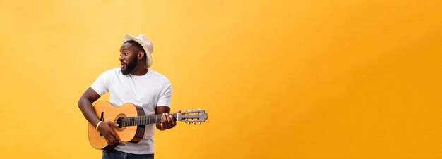 Photo vue latérale d'un homme avec une guitare sur fond jaune