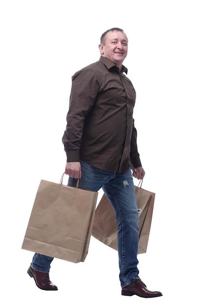 Vue latérale homme heureux avec des sacs à provisions marchant à la maison