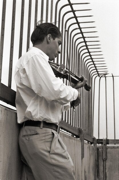 Photo vue latérale d'un homme jouant du violon par la balustrade