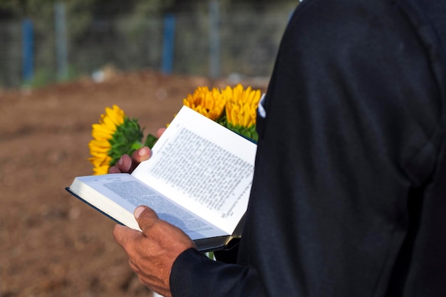 Vue latérale d'un homme juif priant dans la kippa et lisant une Bible hébraïque sur fond de forêt en Israël Mise au point sélective Juif hassidique lisant la Torah par temps chaud Homme d'affaires lisant un livre papier