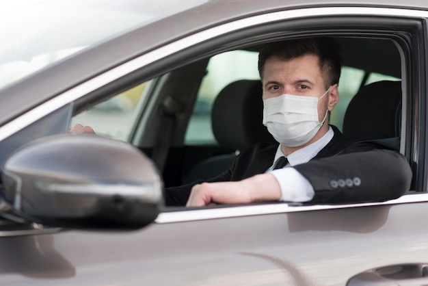 Photo vue latérale de l'homme moderne en voiture avec masque