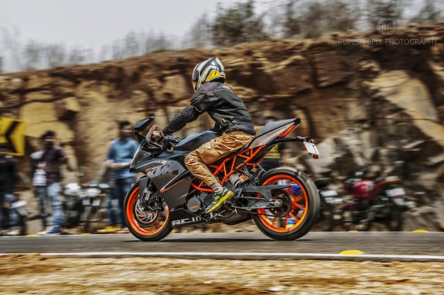 Photo vue latérale d'un homme à moto sur la route contre des formations rocheuses