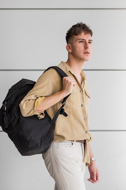 Photo vue latérale de l'homme posant à l'extérieur avec sac à dos