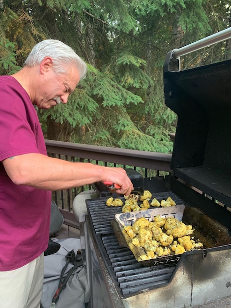 Photo vue latérale d'un homme préparant de la nourriture sur un gril à barbecue