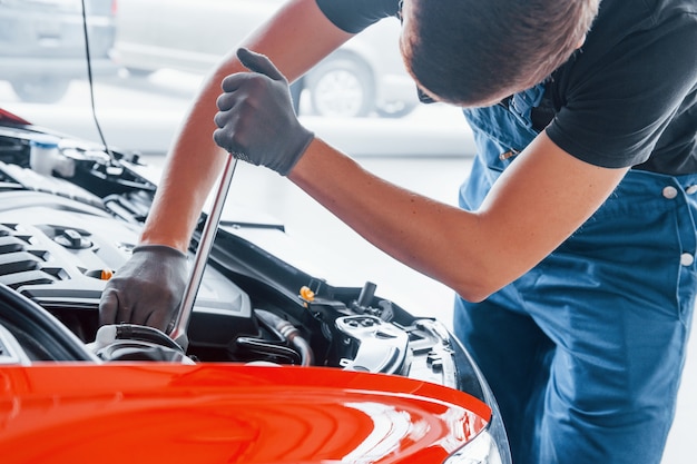 Vue latérale de l'homme en uniforme qui fonctionne avec une automobile cassée. Conception de service automobile