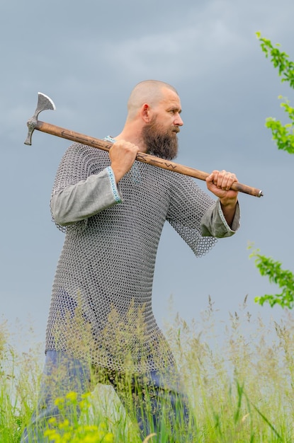 Vue latérale d'un homme en vêtements vikings médiévaux Casque métallique et cotte de mailles Menace avec une hache