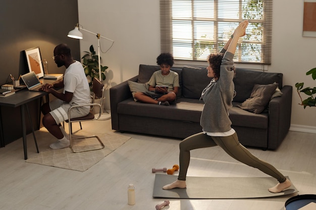 Vue latérale d'une jeune femme active pratiquant des exercices d'étirement sur un tapis