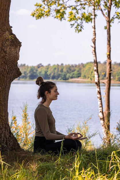 Photo vue latérale d'une jeune femme assise au bord du lac