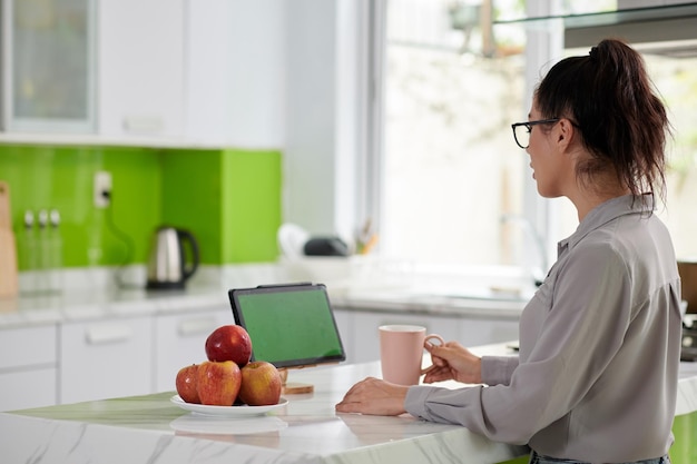 Vue latérale d'une jeune femme en chemise décontractée regardant un écran vert de tablette