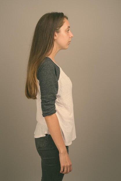 Photo vue latérale d'une jeune femme debout contre le mur