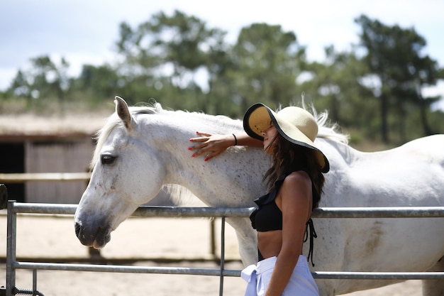 Vue latérale d'une jeune femme debout près d'un cheval
