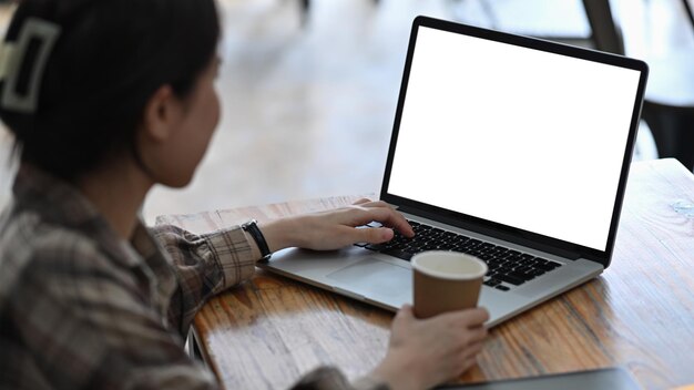 Vue latérale jeune femme dorée tasse à café et à l'aide d'un ordinateur portable